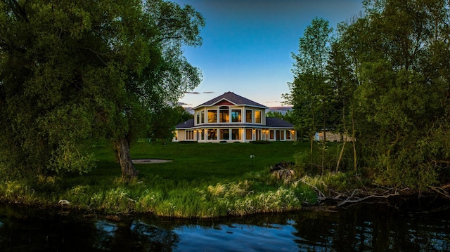 back of property featuring a water view and a lawn