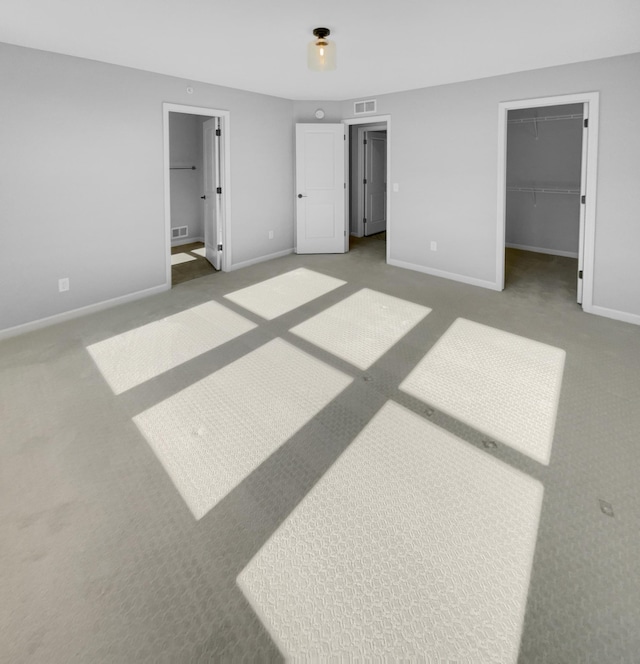 unfurnished bedroom with carpet flooring, a walk in closet, a closet, and ensuite bath