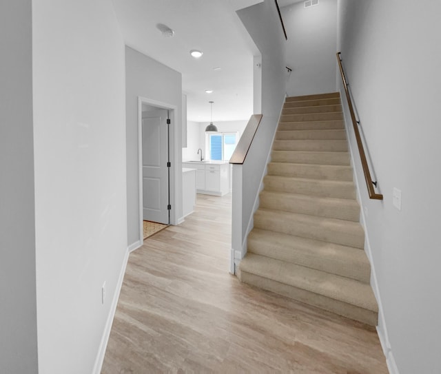 staircase featuring sink and hardwood / wood-style flooring