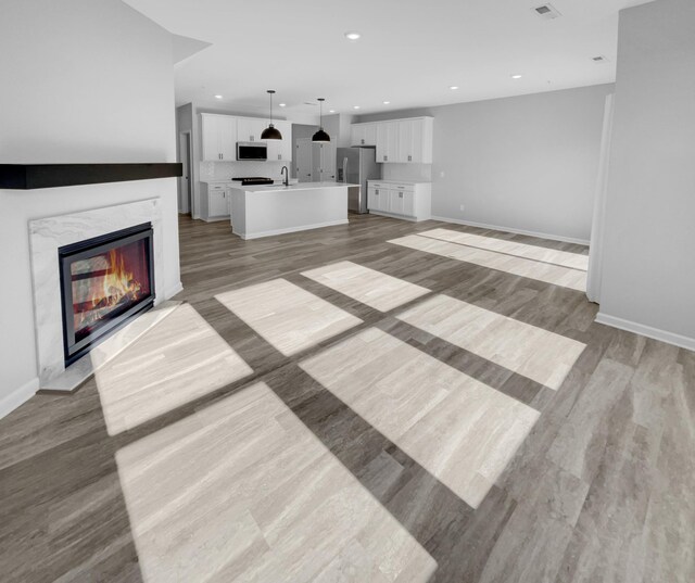 unfurnished living room with sink, a high end fireplace, and light hardwood / wood-style flooring