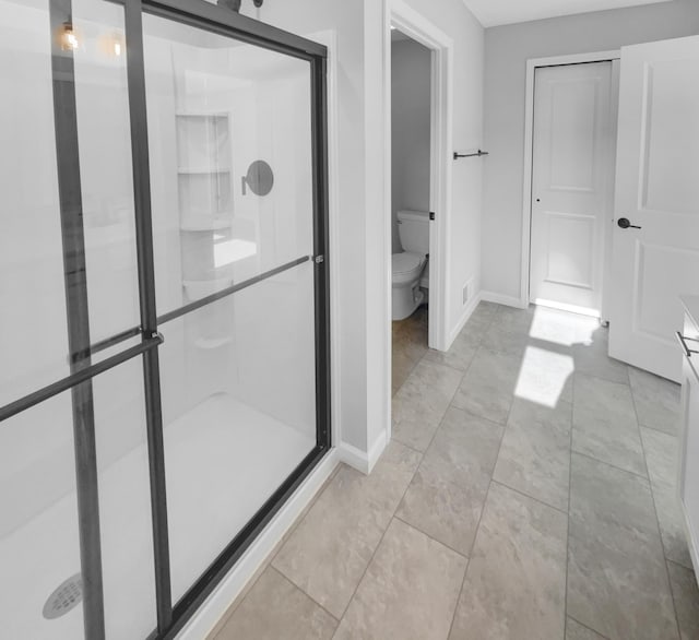 bathroom featuring walk in shower, tile patterned flooring, vanity, and toilet