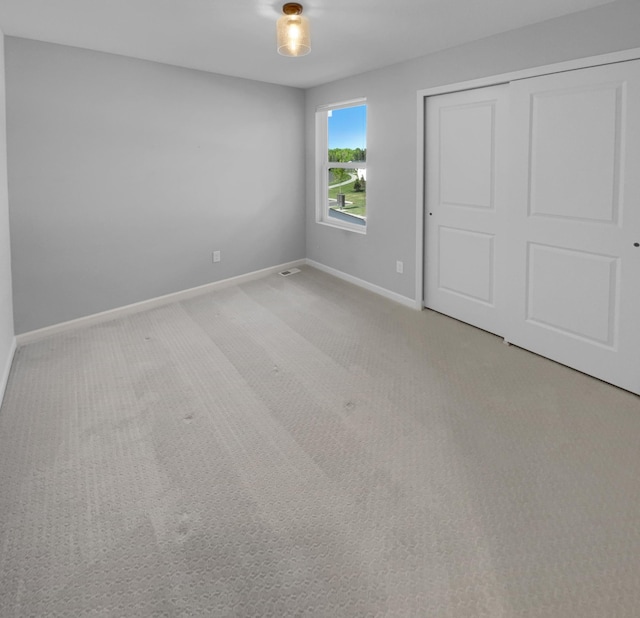 unfurnished bedroom featuring light carpet and a closet