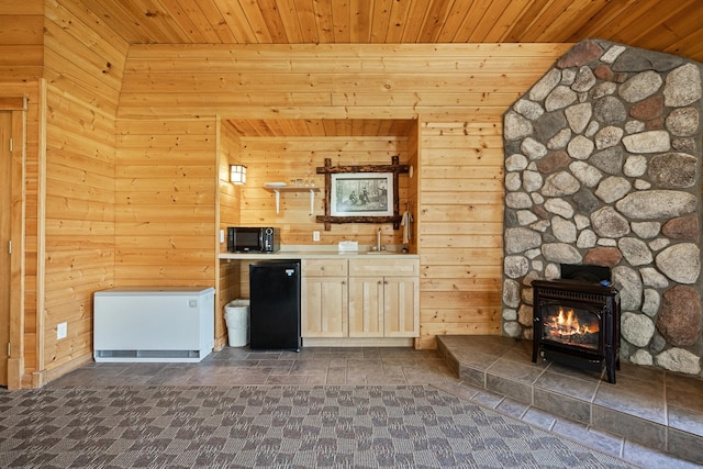 kitchen with sink, wooden walls, wood ceiling, and refrigerator