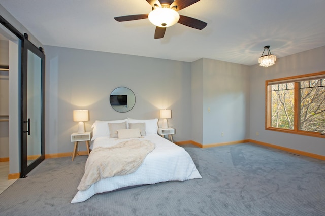 carpeted bedroom with ceiling fan with notable chandelier and a barn door