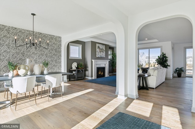 dining area featuring an inviting chandelier, a fireplace, and wood-type flooring