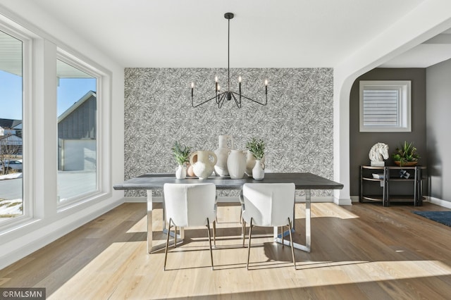 dining space with a healthy amount of sunlight, wood-type flooring, and a notable chandelier