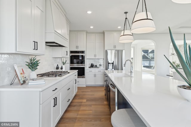 kitchen with stainless steel appliances, decorative light fixtures, dark hardwood / wood-style flooring, white cabinets, and sink