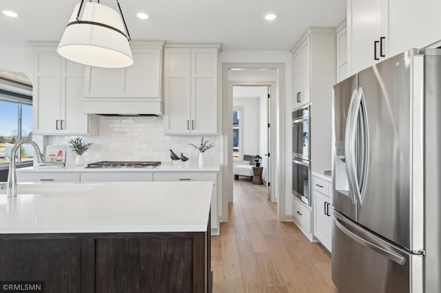 kitchen featuring stainless steel appliances, backsplash, hanging light fixtures, white cabinets, and sink