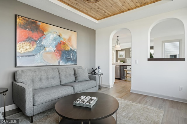 living room featuring wooden ceiling, light hardwood / wood-style floors, and a raised ceiling