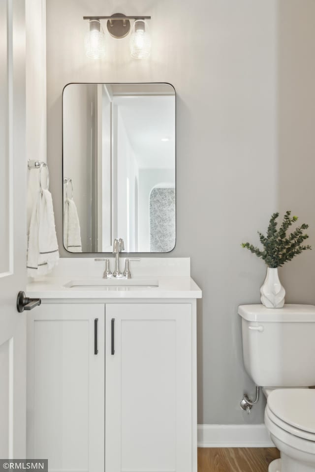 bathroom featuring toilet, vanity, and hardwood / wood-style flooring