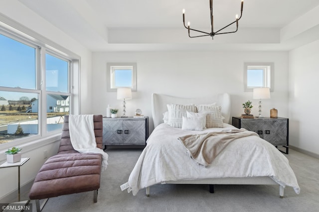 carpeted bedroom with a raised ceiling, a notable chandelier, and multiple windows