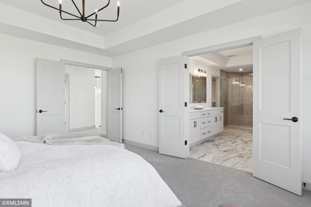 bedroom with connected bathroom, a tray ceiling, and a chandelier