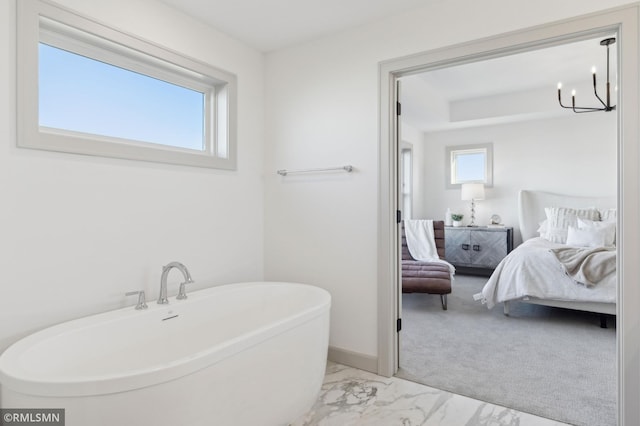 bathroom with a bathing tub, a notable chandelier, and a healthy amount of sunlight