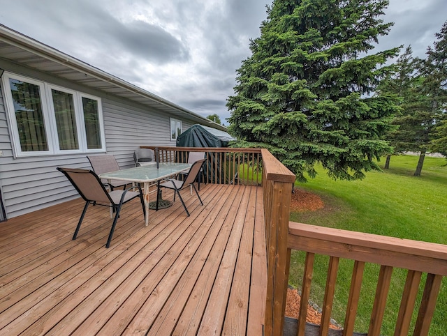 wooden deck with outdoor dining area and a yard