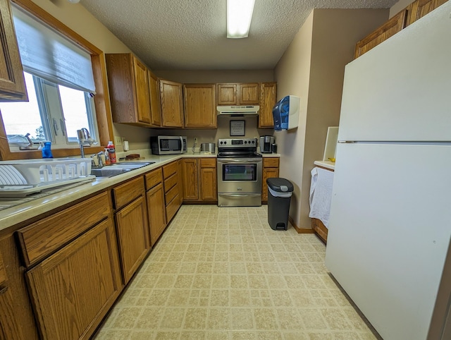 kitchen featuring appliances with stainless steel finishes, sink, a textured ceiling, and light tile floors