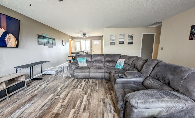 living room with ceiling fan, a textured ceiling, and hardwood / wood-style flooring