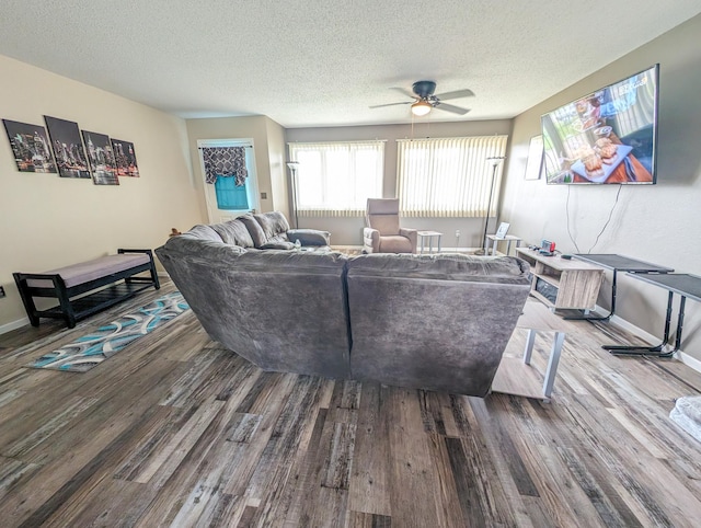 living room with a textured ceiling, baseboards, and wood finished floors