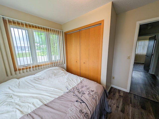 bedroom with a textured ceiling, a closet, baseboards, and wood finished floors