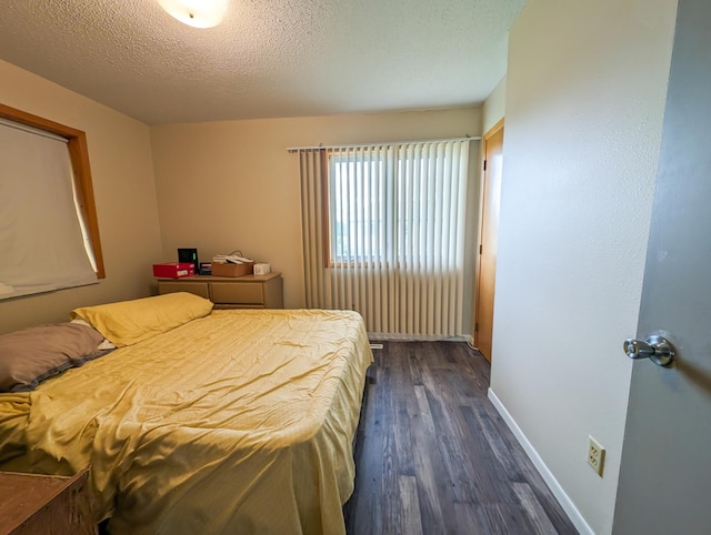 bedroom with dark wood-style floors, baseboards, and a textured ceiling