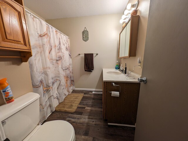 bathroom featuring a textured ceiling, wood-type flooring, vanity, and toilet