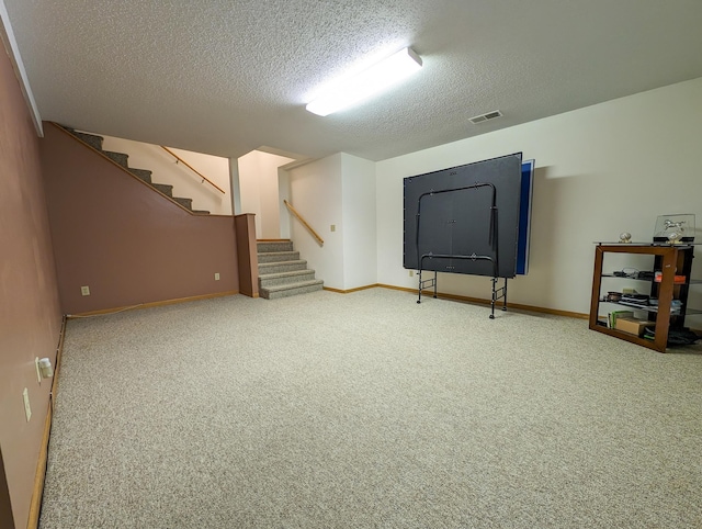 below grade area featuring carpet, visible vents, a textured ceiling, and stairs