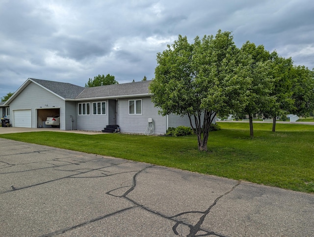 view of front of home featuring concrete driveway, roof with shingles, an attached garage, and a front yard