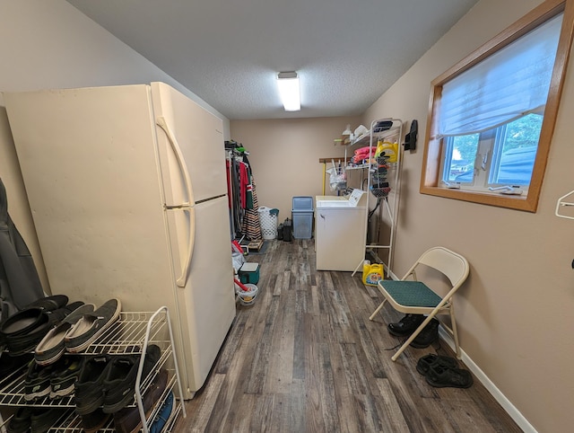 kitchen with a textured ceiling, wood finished floors, baseboards, freestanding refrigerator, and washer / clothes dryer