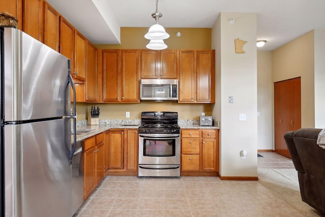 kitchen featuring light stone countertops, stainless steel appliances, hanging light fixtures, and light carpet