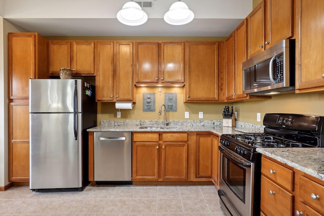 kitchen with light stone countertops, sink, light tile patterned floors, and appliances with stainless steel finishes