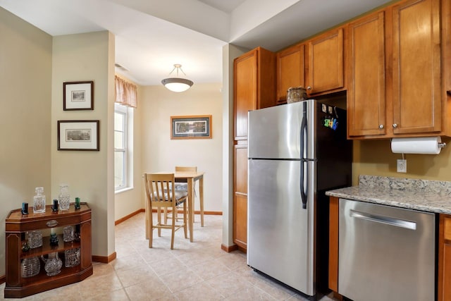 kitchen featuring light tile patterned floors, light stone countertops, and appliances with stainless steel finishes