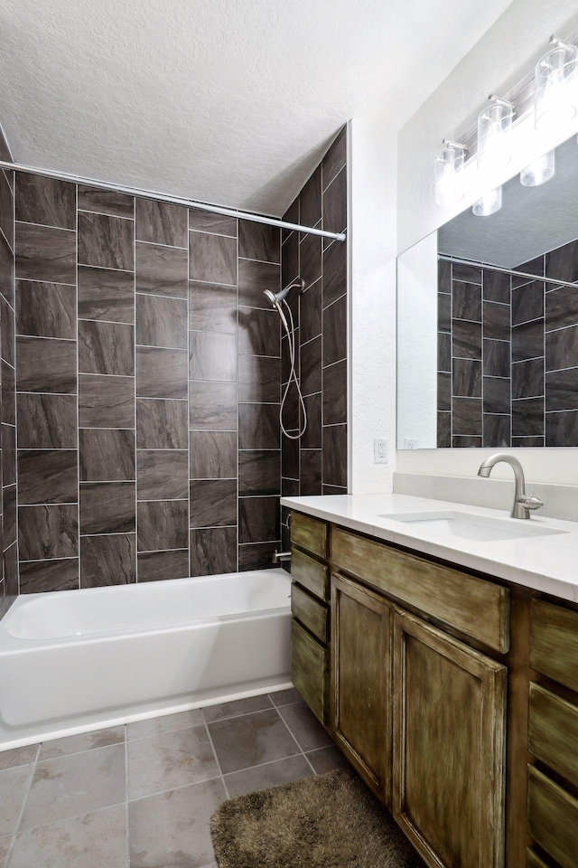 bathroom with tile patterned floors, tiled shower / bath combo, a textured ceiling, and vanity