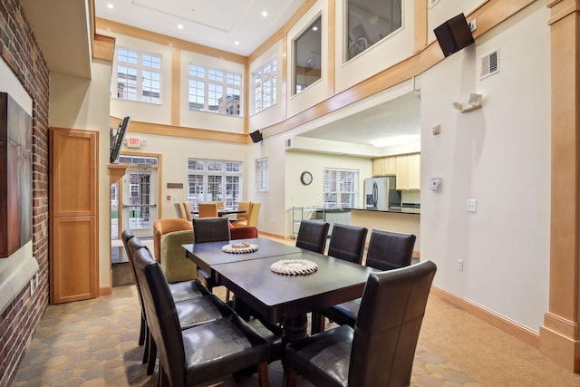 carpeted dining space with a high ceiling