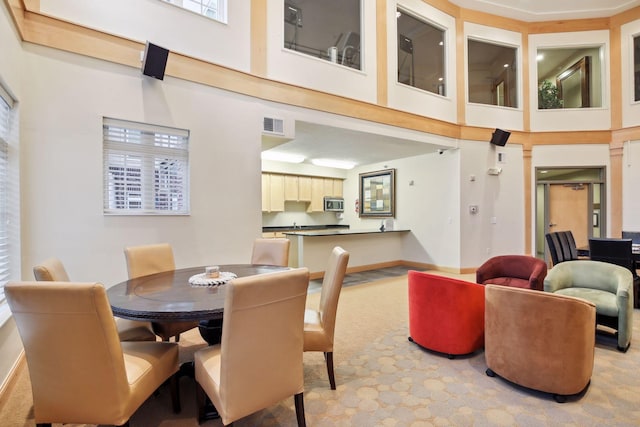 dining area with light carpet and a towering ceiling