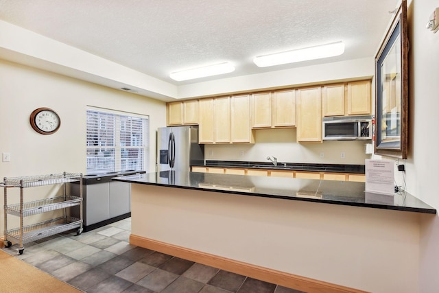 kitchen featuring kitchen peninsula, sink, a textured ceiling, and appliances with stainless steel finishes