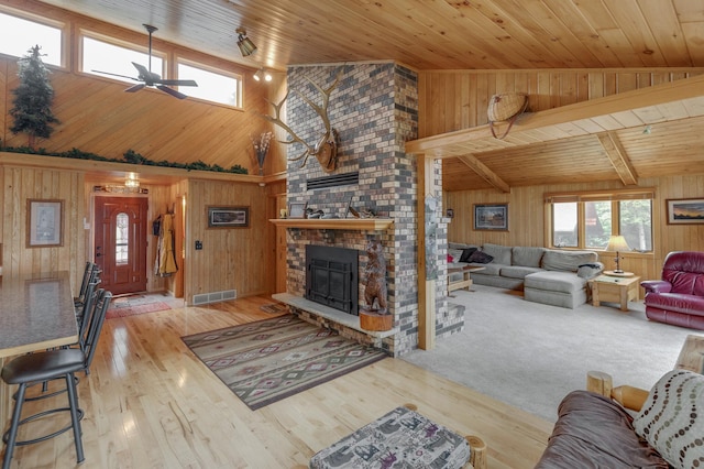 living room with wood ceiling, wooden walls, ceiling fan, and a brick fireplace