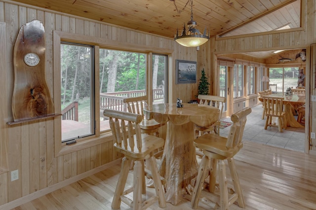 dining space featuring wooden walls, plenty of natural light, vaulted ceiling, and wooden ceiling