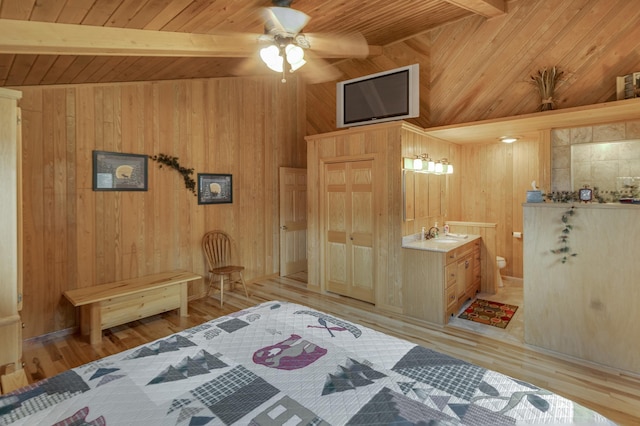 bedroom with wood walls, wooden ceiling, light hardwood / wood-style flooring, ceiling fan, and ensuite bath