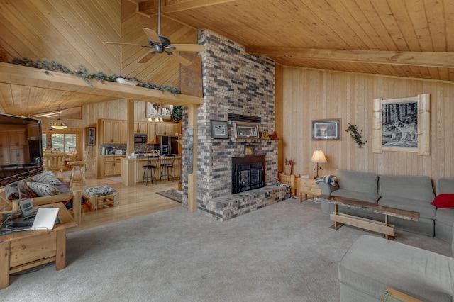 carpeted living room with wooden ceiling, beamed ceiling, ceiling fan, and a brick fireplace