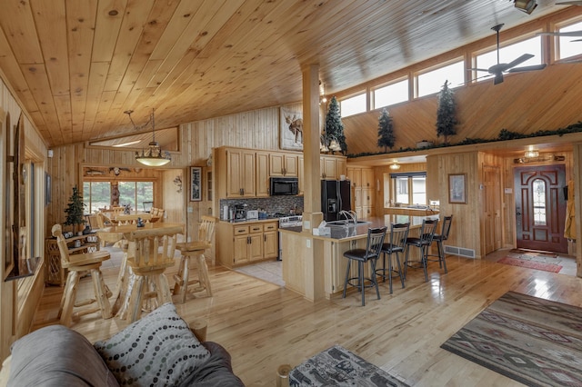 living room featuring wood ceiling, high vaulted ceiling, wood walls, light hardwood / wood-style flooring, and sink