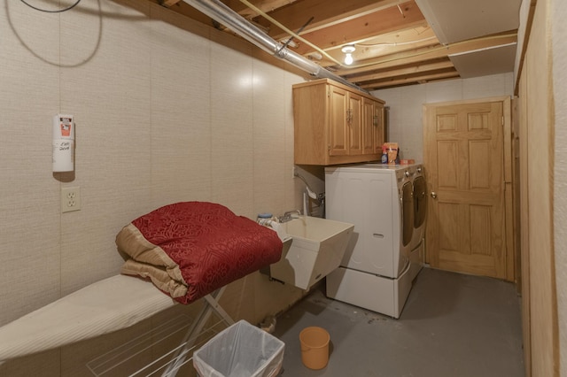 clothes washing area featuring cabinets, washing machine and dryer, and sink