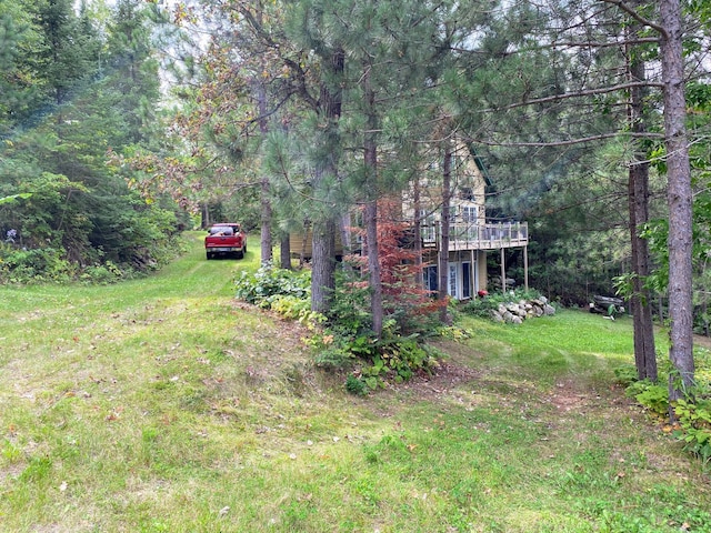 view of yard with a wooden deck and a view of trees