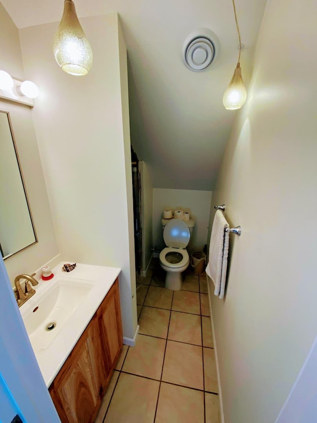 bathroom with vaulted ceiling, tile patterned flooring, toilet, and vanity