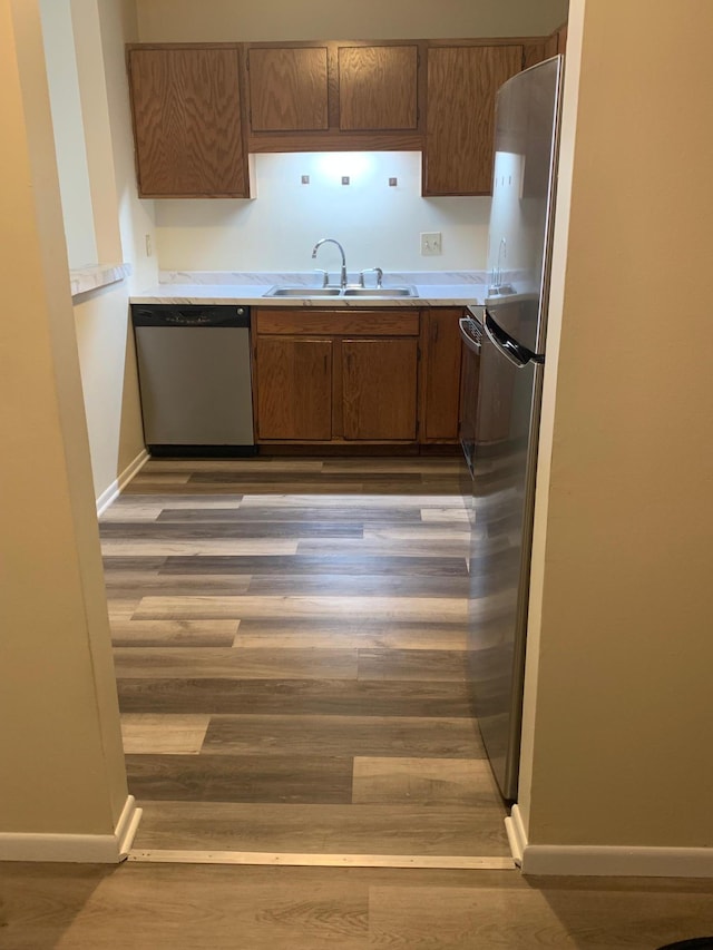 kitchen with baseboards, light countertops, stainless steel appliances, and a sink