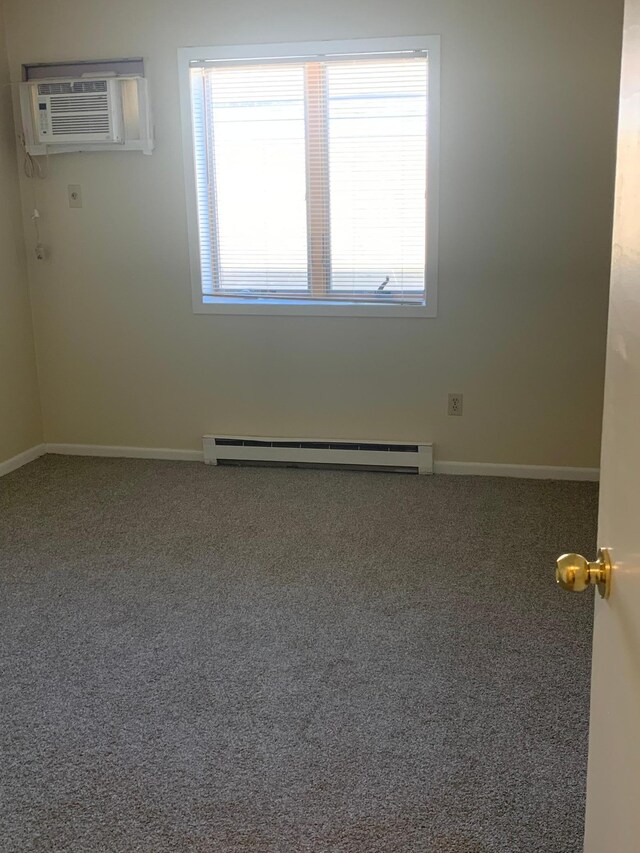 carpeted spare room featuring baseboards, a baseboard radiator, a wall unit AC, and plenty of natural light