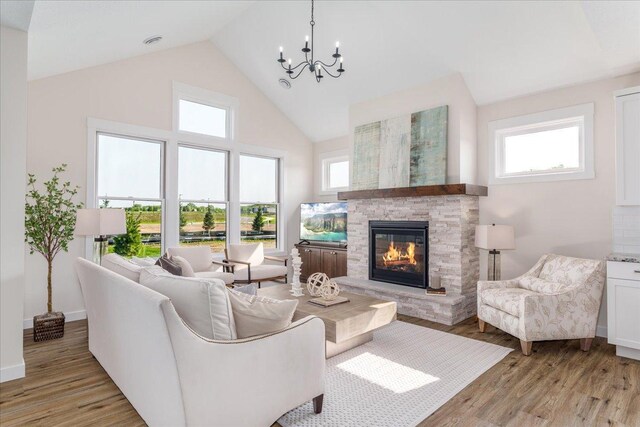 living room with a fireplace, a notable chandelier, light hardwood / wood-style flooring, and high vaulted ceiling