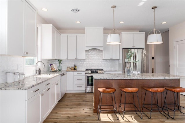 kitchen with sink, white cabinetry, a center island, hanging light fixtures, and stainless steel appliances