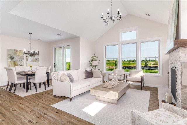 living room featuring wood-type flooring, a fireplace, a chandelier, and high vaulted ceiling