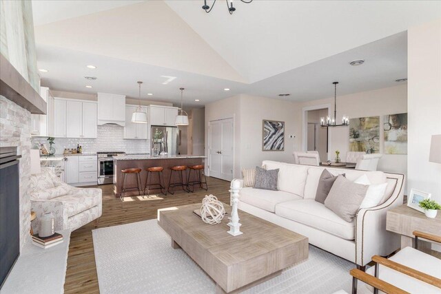 living room with wood-type flooring, a chandelier, and high vaulted ceiling