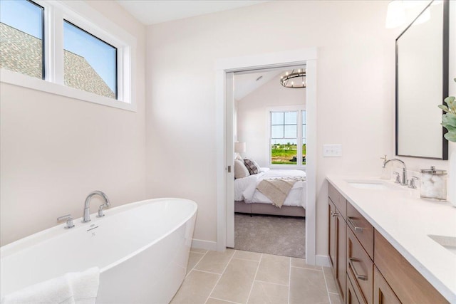 bathroom with lofted ceiling, a tub to relax in, tile patterned flooring, and vanity