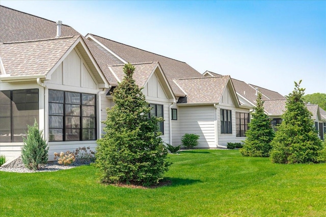 rear view of property with a sunroom and a lawn